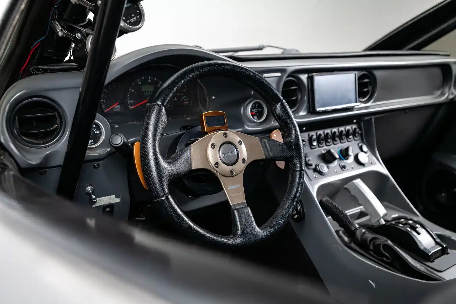 Innenraumansicht des Local Motors Rally Fighter mit Momo-Lenkrad, Mittelkonsole und Cockpit-Details.