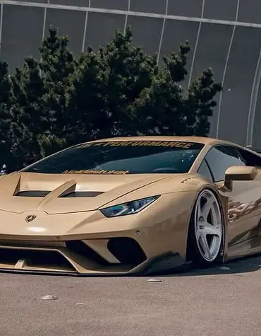 Goldener Liberty Walk LB‑Silhouette Works Lamborghini Huracán LP610‑4 mit breitem Bodykit auf einer Messe.