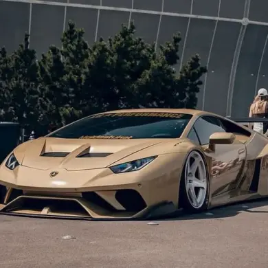 Goldener Liberty Walk LB‑Silhouette Works Lamborghini Huracán LP610‑4 mit breitem Bodykit auf einer Messe.