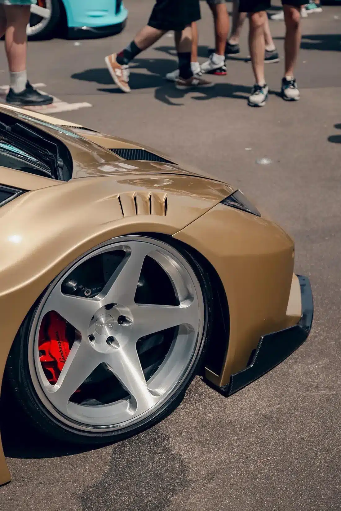 Nahaufnahme des vorderen Kotflügels eines goldenen Liberty Walk Lamborghini Huracán LB‑Silhouette Works mit Rotiform ROC Felge und roten Bremssätteln.