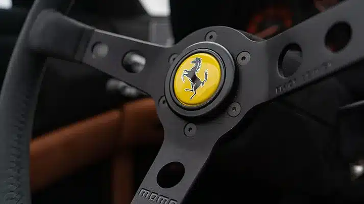 Nahaufnahme eines Momo-Sportlenkrads mit gelbem Ferrari-Logo im Liberty Walk LB-Works Ferrari 348TS.