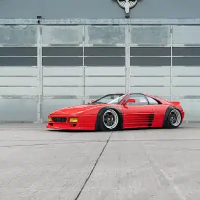 Liberty Walk LB-Works Ferrari 348TS, Baujahr 1990, in Rot und mit verbreiterten Kotflügeln vor einer Industriehalle.