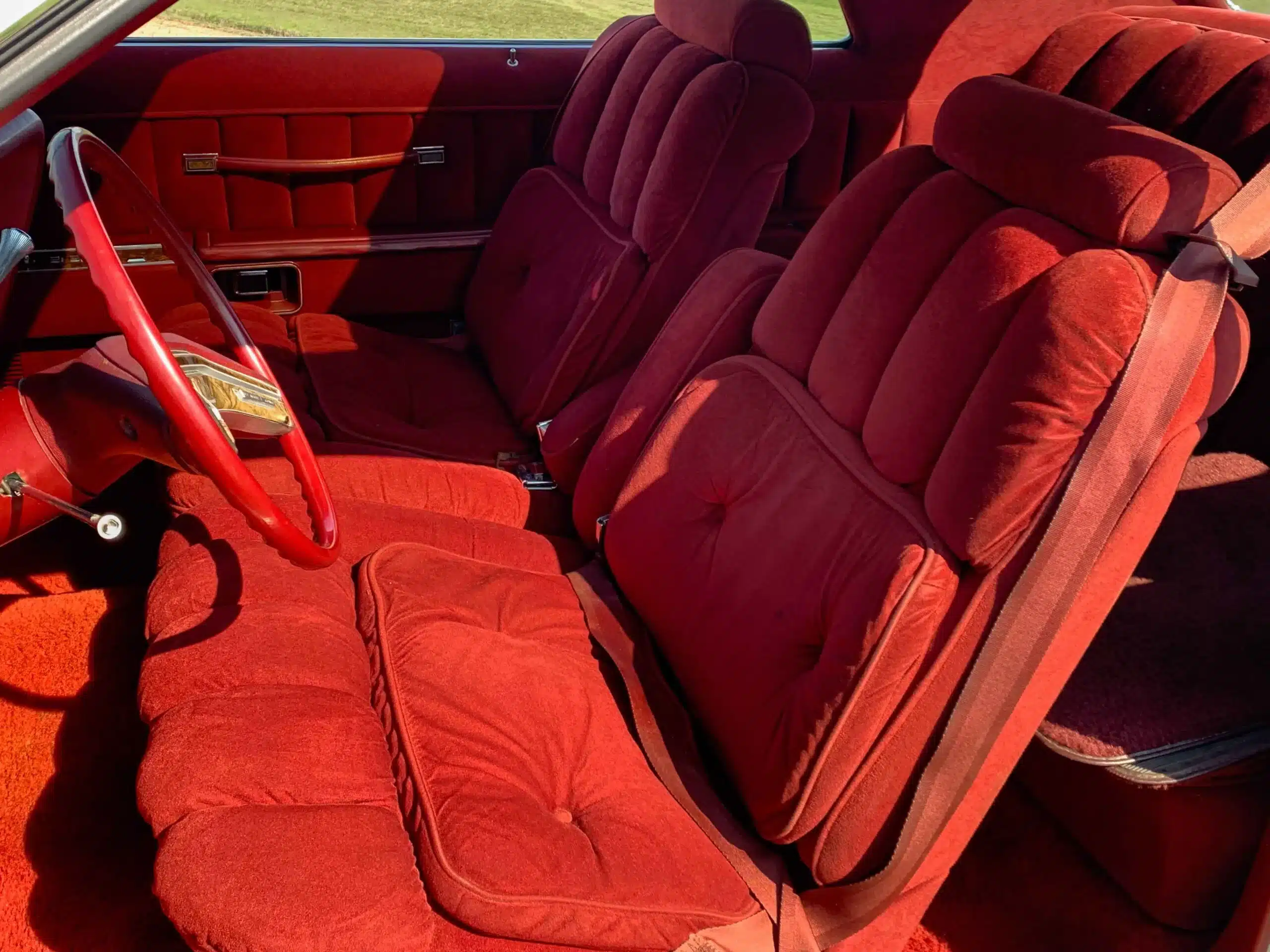 Roter Fahrzeuginnenraum des Lincoln Continental MK V von 1977 mit breiten Polstersitzen und Lenkrad.