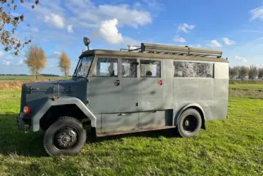 Seitenansicht eines Magirus-Deutz 85 D 11 AWD Busses der 1960er Jahre mit robuster Karosserie, fotografiert auf einer Wiese unter blauem Himmel.