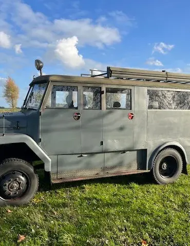 Seitenansicht eines Magirus-Deutz 85 D 11 AWD Busses der 1960er Jahre mit robuster Karosserie, fotografiert auf einer Wiese unter blauem Himmel.