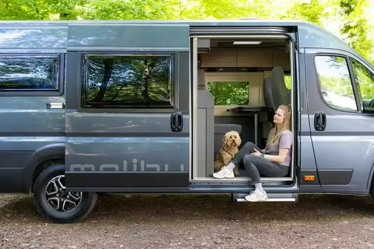 Malibu relax 640 LE R Kastenwagen, geöffnet, mit Frau und Hund am großzügigen Seiteneinstieg.