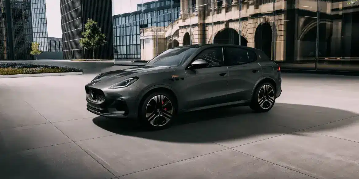 Grauer Maserati Grecale Folgore 2026 vor moderner Glasfassade, seitliche Ansicht.