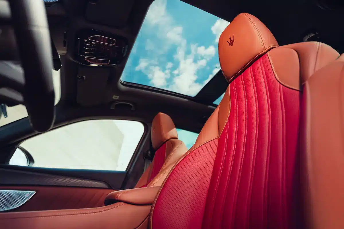 Detailaufnahme des Innenraums eines Maserati Grecale Tributo Il Bruciato mit rot-braunen Ledersitzen und Panorama-Glasdach