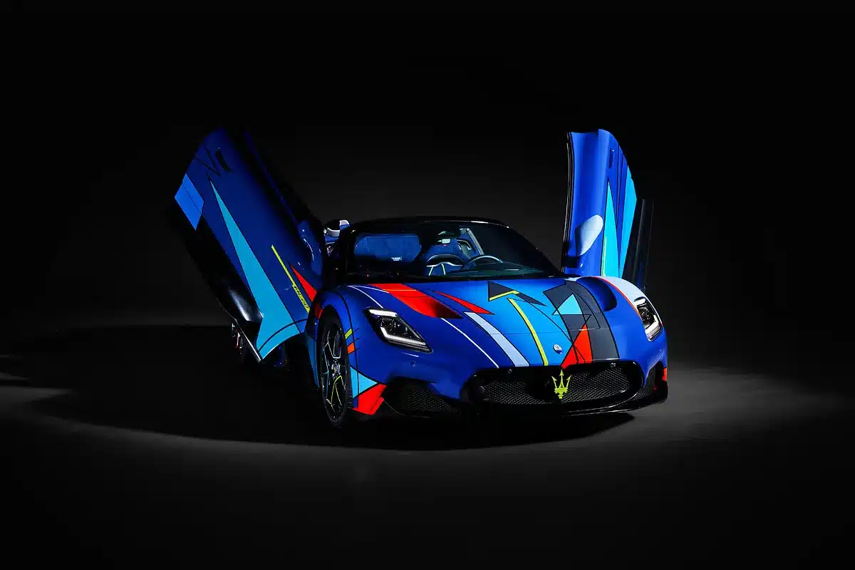 Maserati MC20 Cielo Opera d’Arte mit bunter, abstrakter Lackierung und geöffneten Türen vor schwarzem Hintergrund.