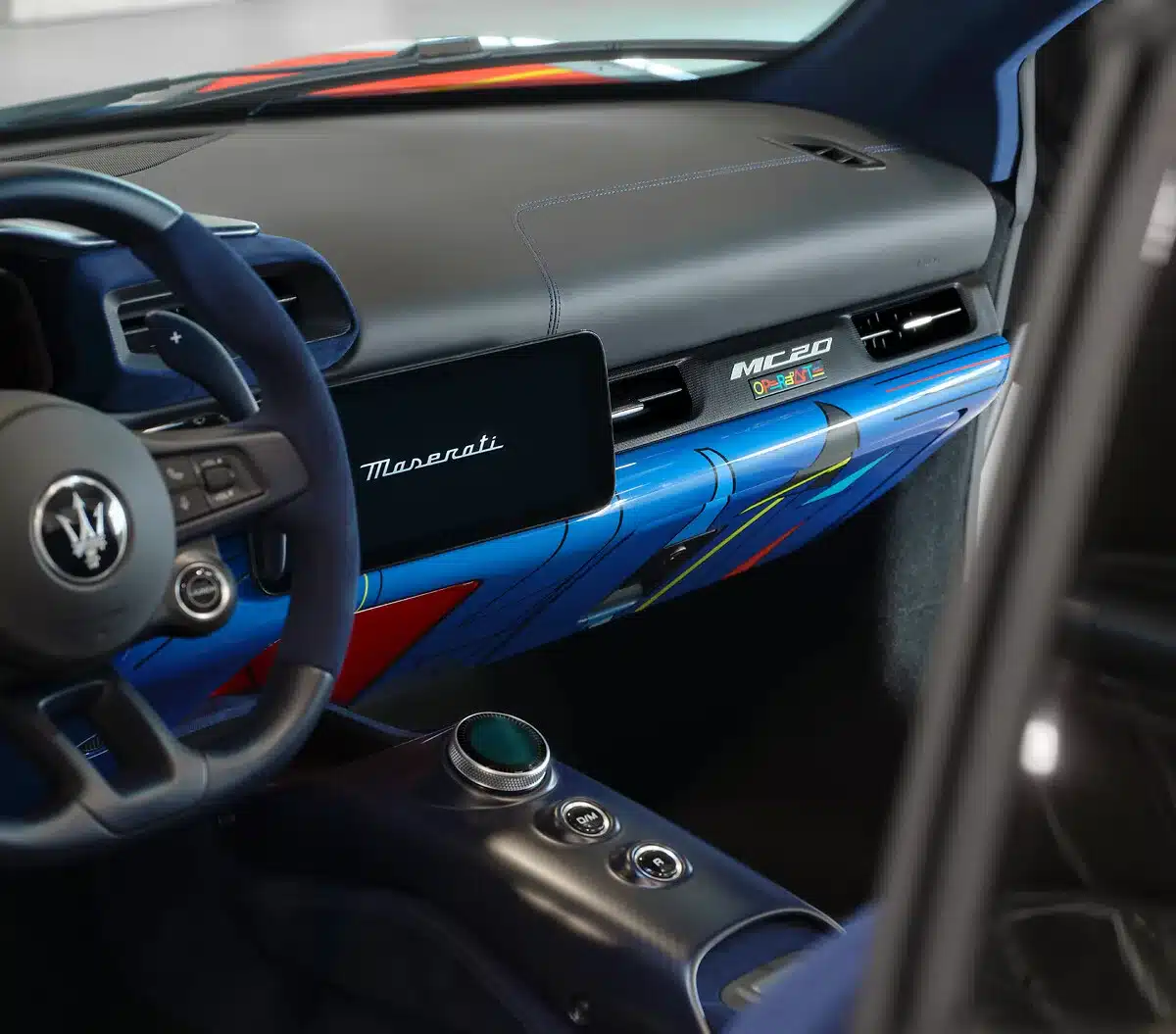 Detailaufnahme des kunstvoll gestalteten Armaturenbretts im Maserati MC20 Cielo 'Opera d’Arte', mit Maserati-Logo und bunten Farbakzenten.