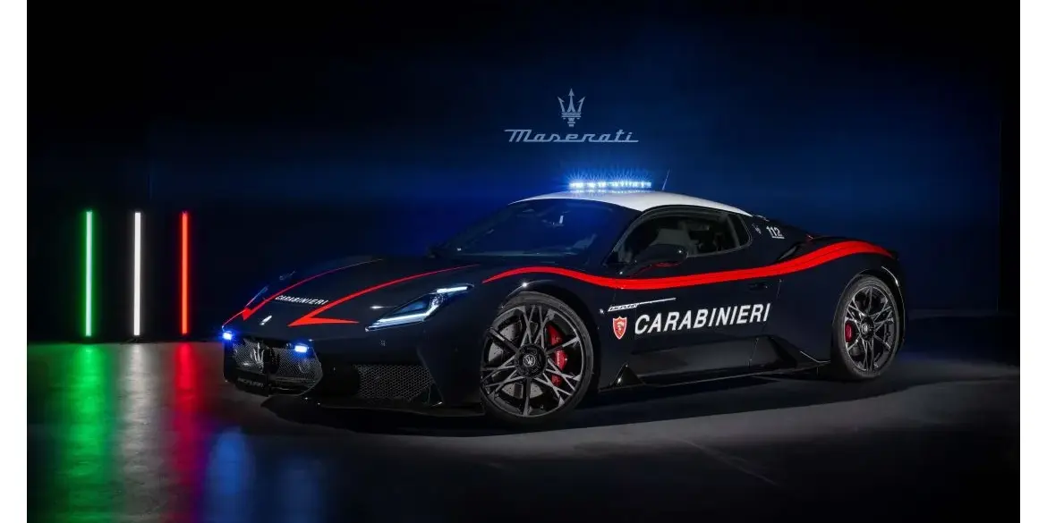 Maserati MCPURA als Carabinieri-Einsatzfahrzeug mit Polizei-Beklebung und Blaulicht, aufgenommen vor dunklem Hintergrund mit italienischer Flagge aus Lichtstreifen.