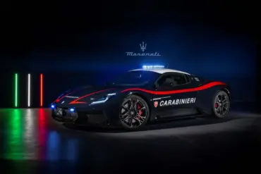 Maserati MCPURA als Carabinieri-Einsatzfahrzeug mit Polizei-Beklebung und Blaulicht, aufgenommen vor dunklem Hintergrund mit italienischer Flagge aus Lichtstreifen.