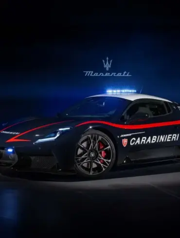 Maserati MCPURA als Carabinieri-Einsatzfahrzeug mit Polizei-Beklebung und Blaulicht, aufgenommen vor dunklem Hintergrund mit italienischer Flagge aus Lichtstreifen.