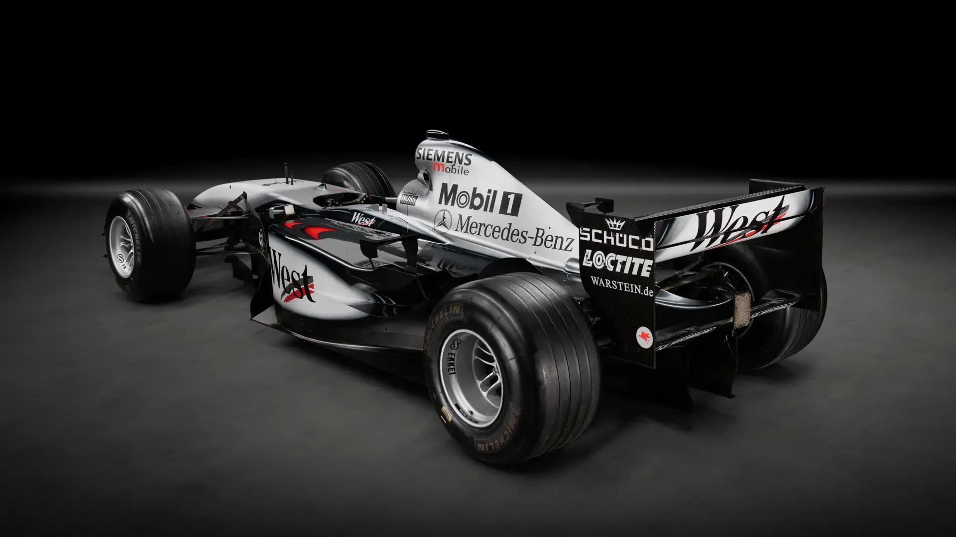 Heckansicht eines McLaren MP4-17A Formel-1-Rennwagens mit West-Lackierung und Sponsorenlogos in einem Studio-Setting.