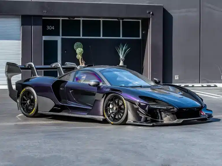 McLaren Senna GTR in dunkler Lackierung mit großem Heckflügel auf einem Parkplatz, seitliche Ansicht.