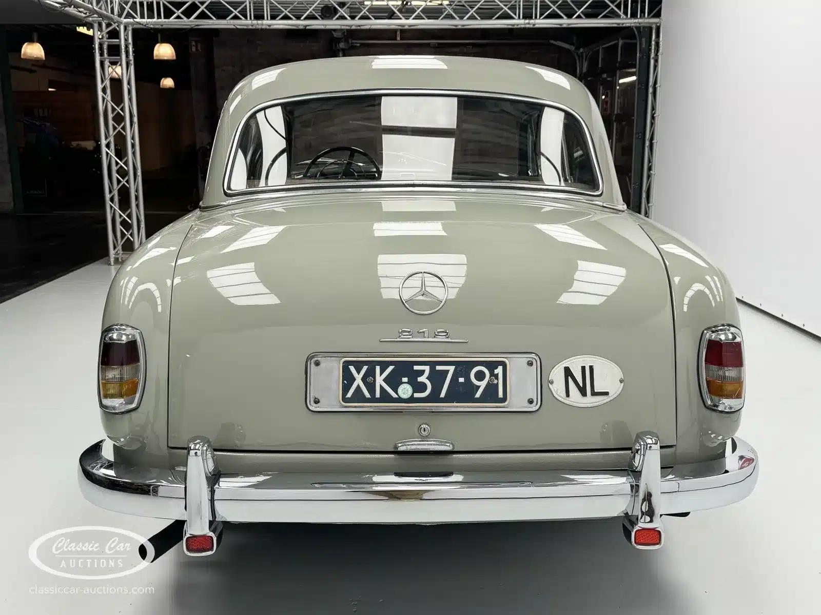 Rückansicht eines Mercedes-Benz 219 S Baujahr 1957 mit niederländischem Kennzeichen in einer Fotohalle.