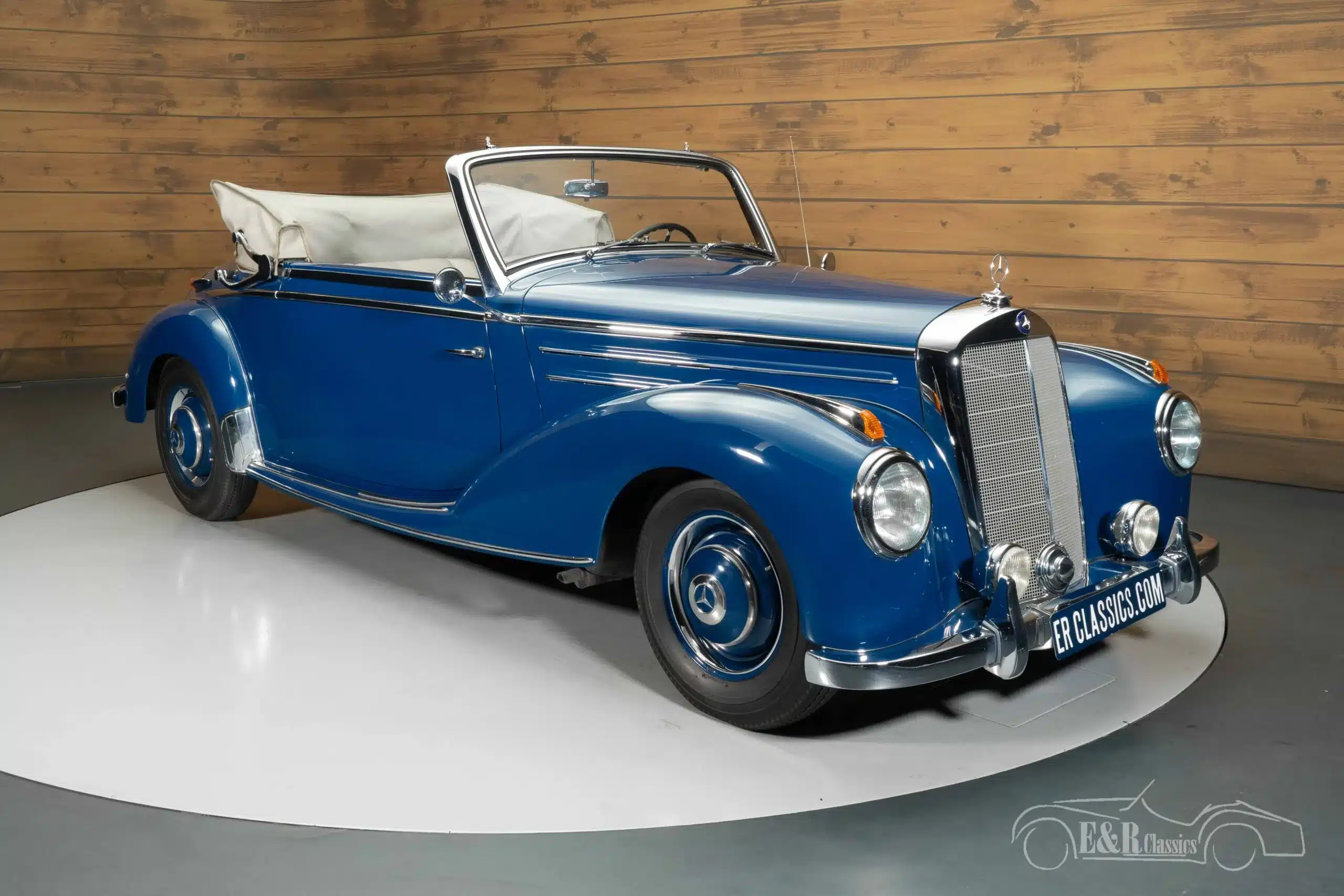 Blaues Mercedes-Benz 220 A Cabriolet von 1951 mit beigem Stoffverdeck und verchromten Details, frontal seitlich aufgenommen