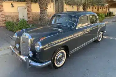 Mercedes-Benz 220 S Ponton Limousine, dunkelgrau, Baujahr 1950er, geparkt an einer Straße unter Palmen.