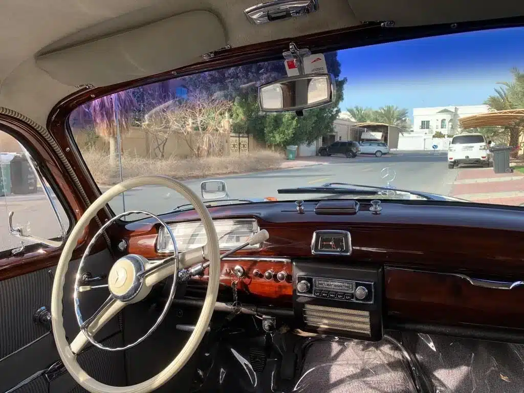 Innenansicht des Mercedes-Benz 220 S Ponton mit klassischen Holz- und Chromdetails am Armaturenbrett.