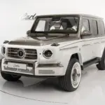 Mercedes-Benz G63 AMG Himalaya mit pastellweißer und goldener Diamantlackierung seitlich frontal im Studio