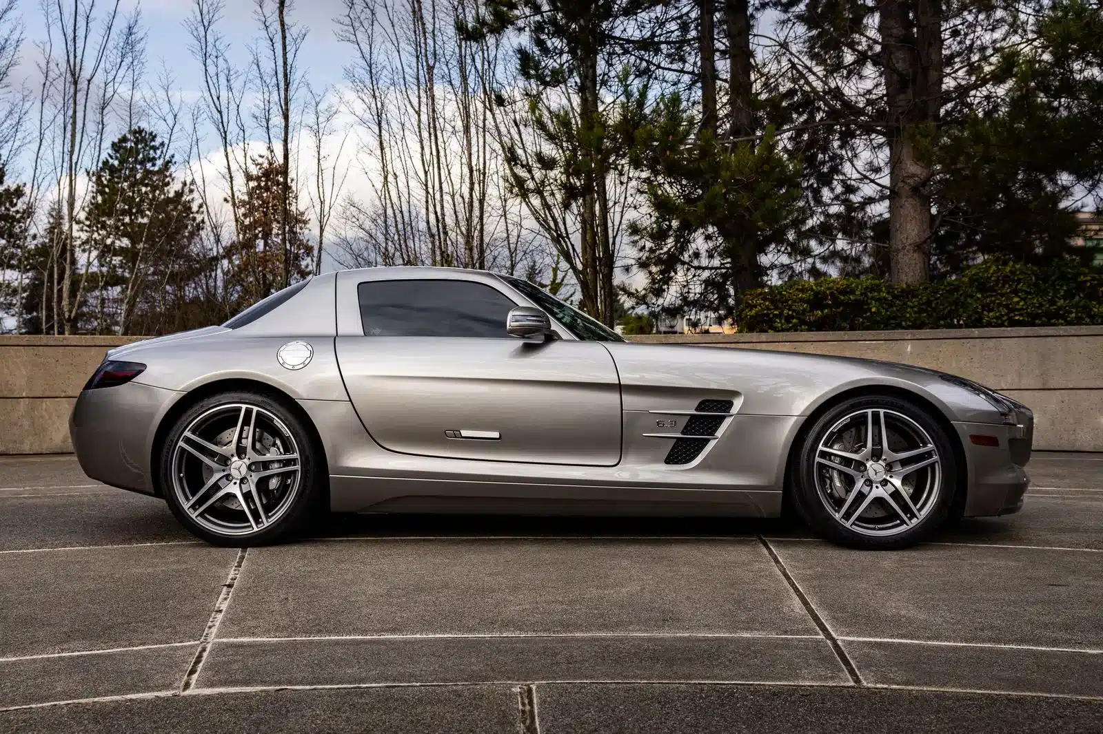Mercedes-Benz SLS AMG Gullwing in Alubeam-Silver im Freien, seitliche Ansicht.