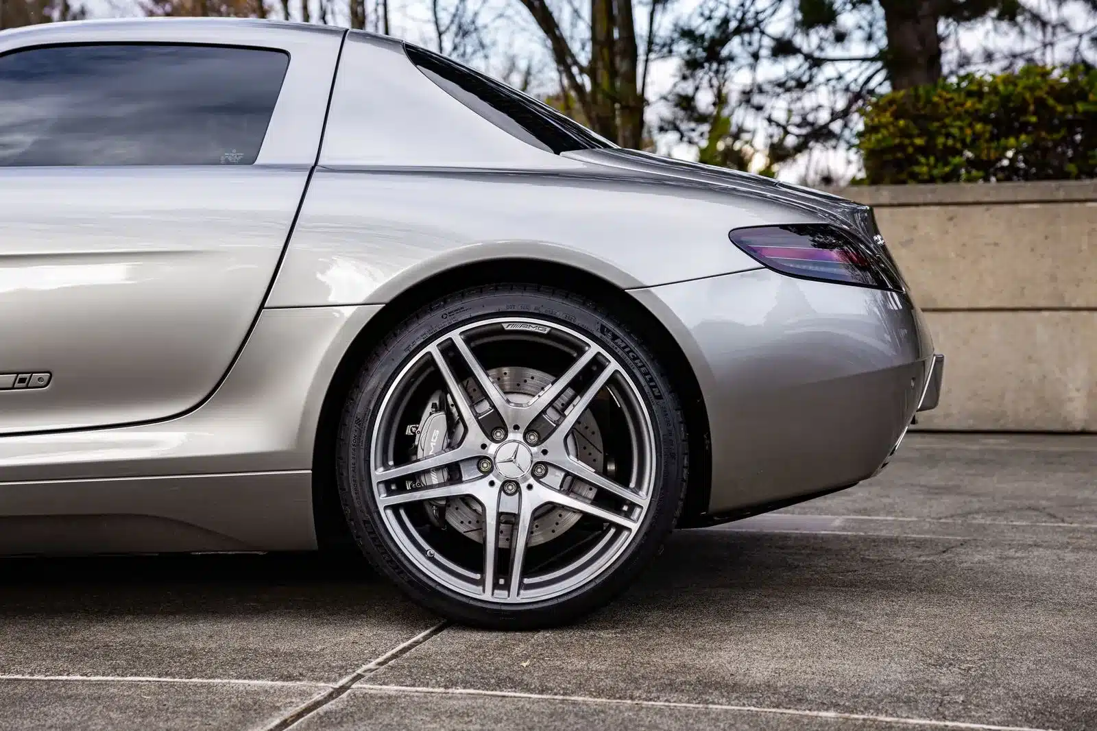 Rückansicht und AMG-Felge eines silbernen Mercedes SLS AMG Gullwing, Nahaufnahme auf der Straße.