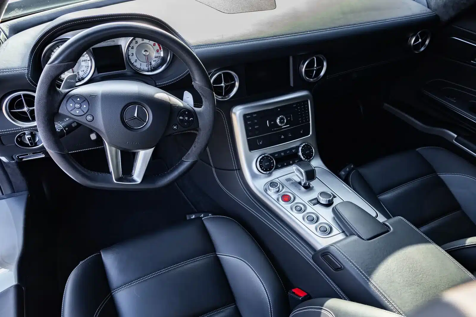 Innenraum und Cockpitansicht eines Mercedes-Benz SLS AMG mit AMG-Lenkrad, analogen Instrumenten und luxuriöser Mittelkonsole.