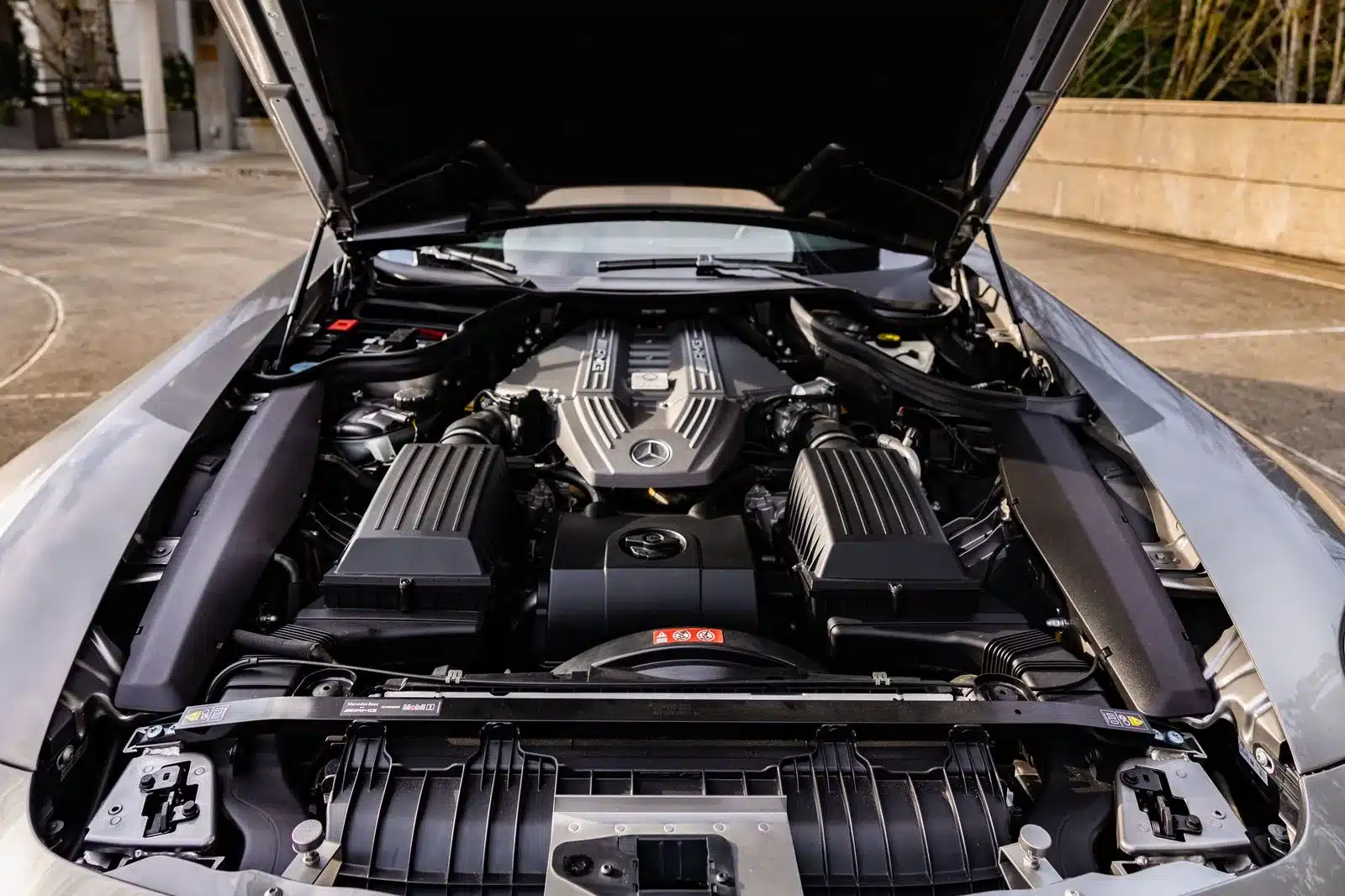 Blick in den Motorraum eines Mercedes-Benz SLS AMG mit geöffnetem Frontdeckel, sichtbar ist der AMG V8-Motor.