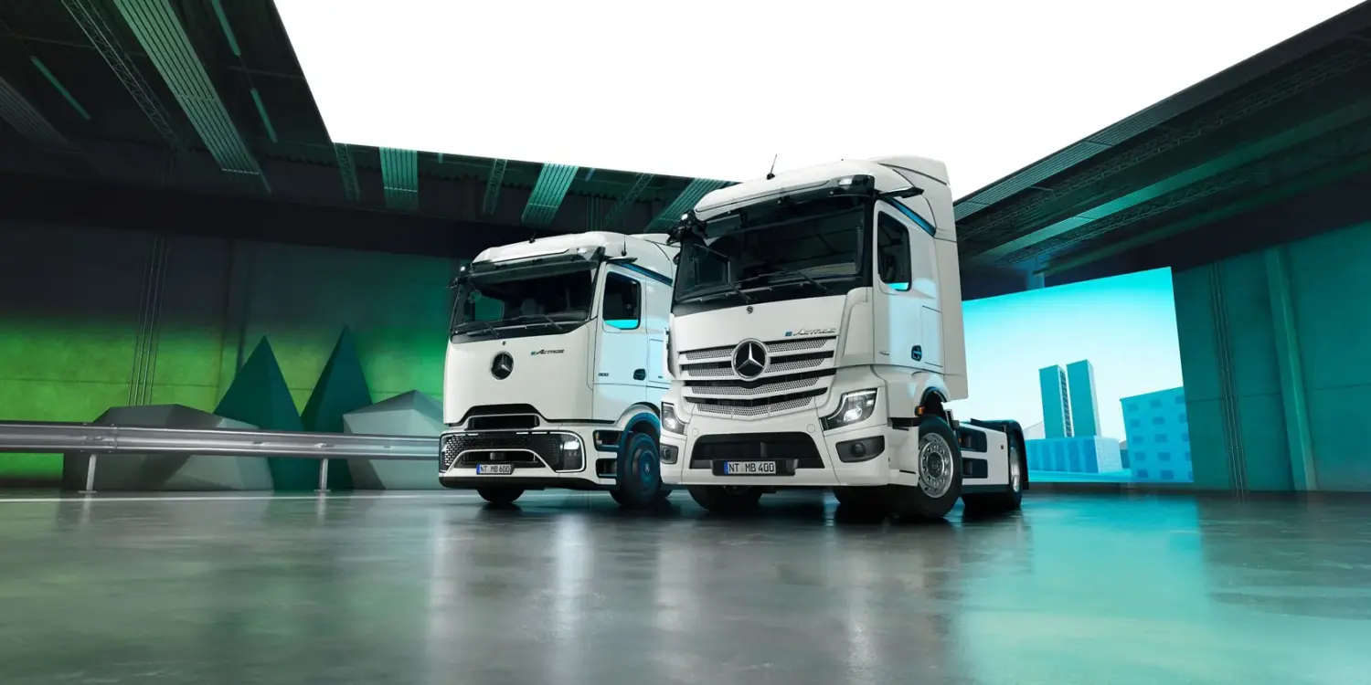 Zwei Mercedes-Benz eActros Elektro-Lkw der neuesten Generation in einer modernen Halle, nebeneinander aufgestellt.