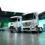 Zwei Mercedes-Benz eActros Elektro-Lkw der neuesten Generation in einer modernen Halle, nebeneinander aufgestellt.