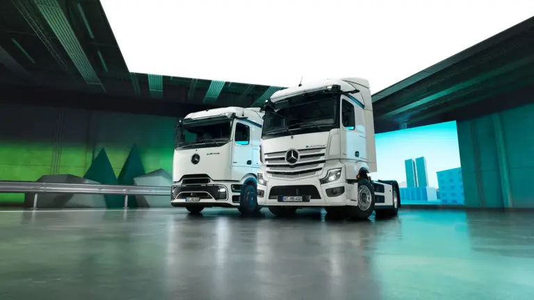 Zwei Mercedes-Benz eActros Elektro-Lkw der neuesten Generation in einer modernen Halle, nebeneinander aufgestellt.