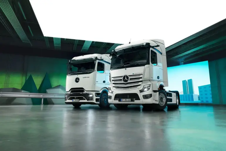 Zwei Mercedes-Benz eActros Elektro-Lkw der neuesten Generation in einer modernen Halle, nebeneinander aufgestellt.