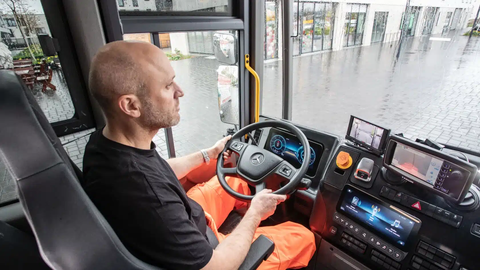 Innenansicht der Fahrerkabine eines Mercedes-Benz eEconic mit Fahrer am Steuer.
