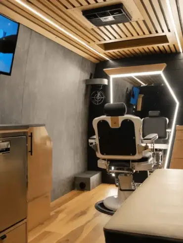 Innenraum eines umgebauten Mercedes Sprinter als mobiler Barbershop mit Barberstuhl, großem Spiegel, TV und moderner Ausstattung.