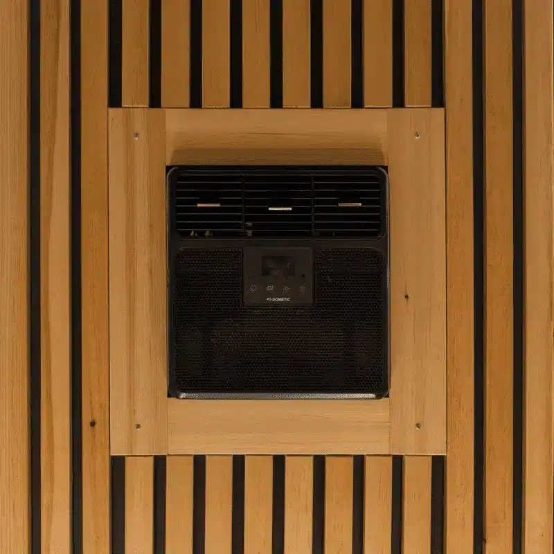 Innenansicht des Dometic RTX 2000 Klimageräts, eingebaut in eine Holzdecke mit Lamellenoptik in einem mobilen Barbershop.