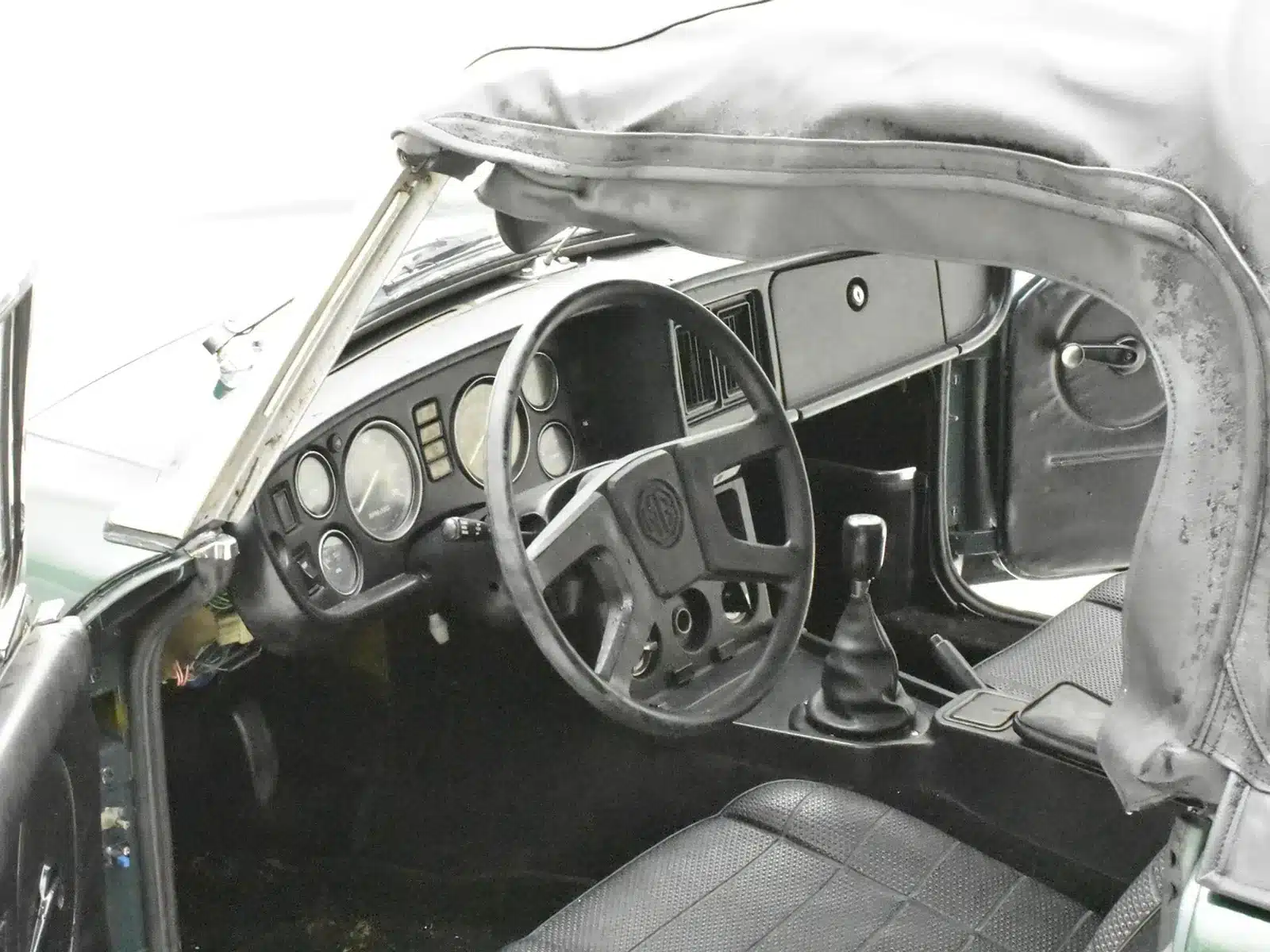 Detailansicht des Cockpits und Lenkrads eines MGB Roadster aus dem Jahr 1980 mit offenem Verdeck