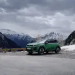 Grüner Citroën C5 Aircross steht auf einer Straße vor schneebedeckten Alpen