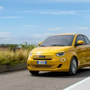 Gelber Fiat 500 Hybrid fährt auf einer Straße im Stadtumfeld bei Tageslicht