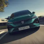 Frontansicht eines grünen Peugeot 308, der auf einer Straße fährt.