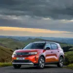 Vauxhall Frontera in Orange vor hügeliger Landschaft bei bewölktem Himmel