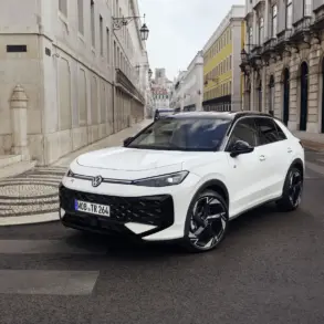 VW T-Roc Kompakt-SUV in weiß auf einer Stadtstraße, mit moderner Architektur im Hintergrund
