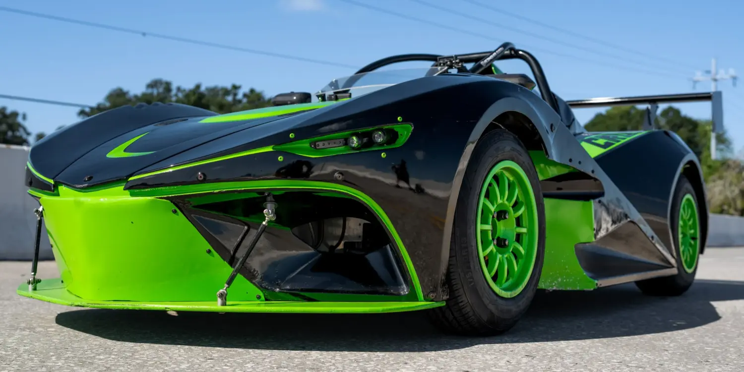 Newstar BG „The Crusher“ in Schwarz mit neon-grünen Akzenten, Frontansicht auf Asphaltstrecke, sportliches Einzelstück mit Flügel und grünen Felgen.
