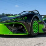 Newstar BG „The Crusher“ in Schwarz mit neon-grünen Akzenten, Frontansicht auf Asphaltstrecke, sportliches Einzelstück mit Flügel und grünen Felgen.