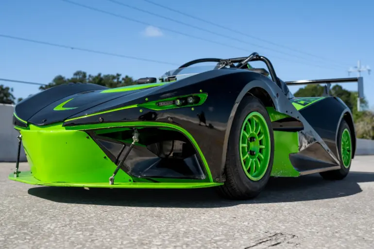 Newstar BG „The Crusher“ in Schwarz mit neon-grünen Akzenten, Frontansicht auf Asphaltstrecke, sportliches Einzelstück mit Flügel und grünen Felgen.