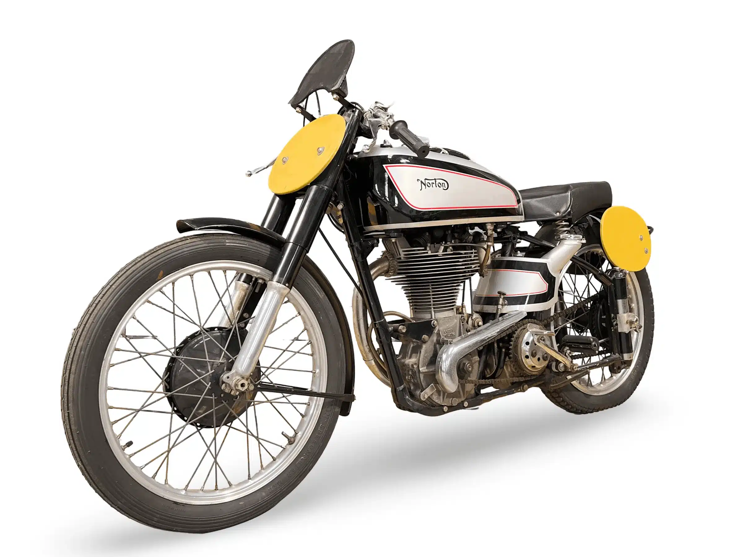 Historische Norton Manx 490 ccm mit DOHC-Einzylindermotor und gelben Startnummerntafeln, seitlich fotografiert.