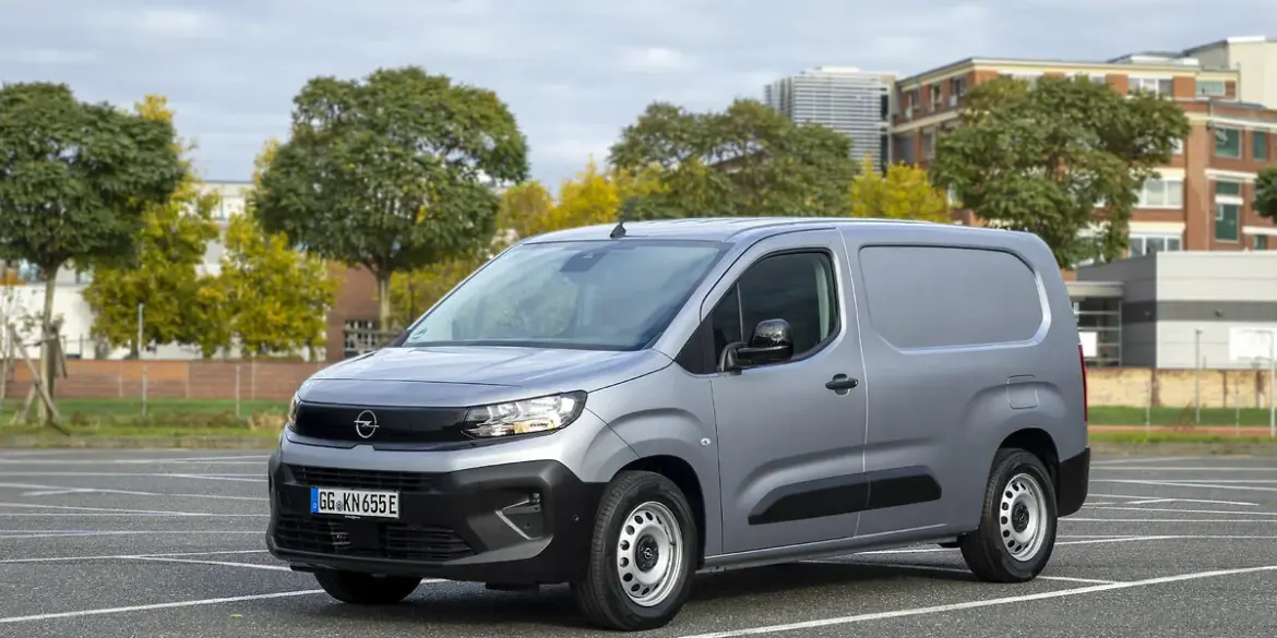 Opel Combo Electric Transporter in Silber auf einem Parkplatz vor städtischer Kulisse.