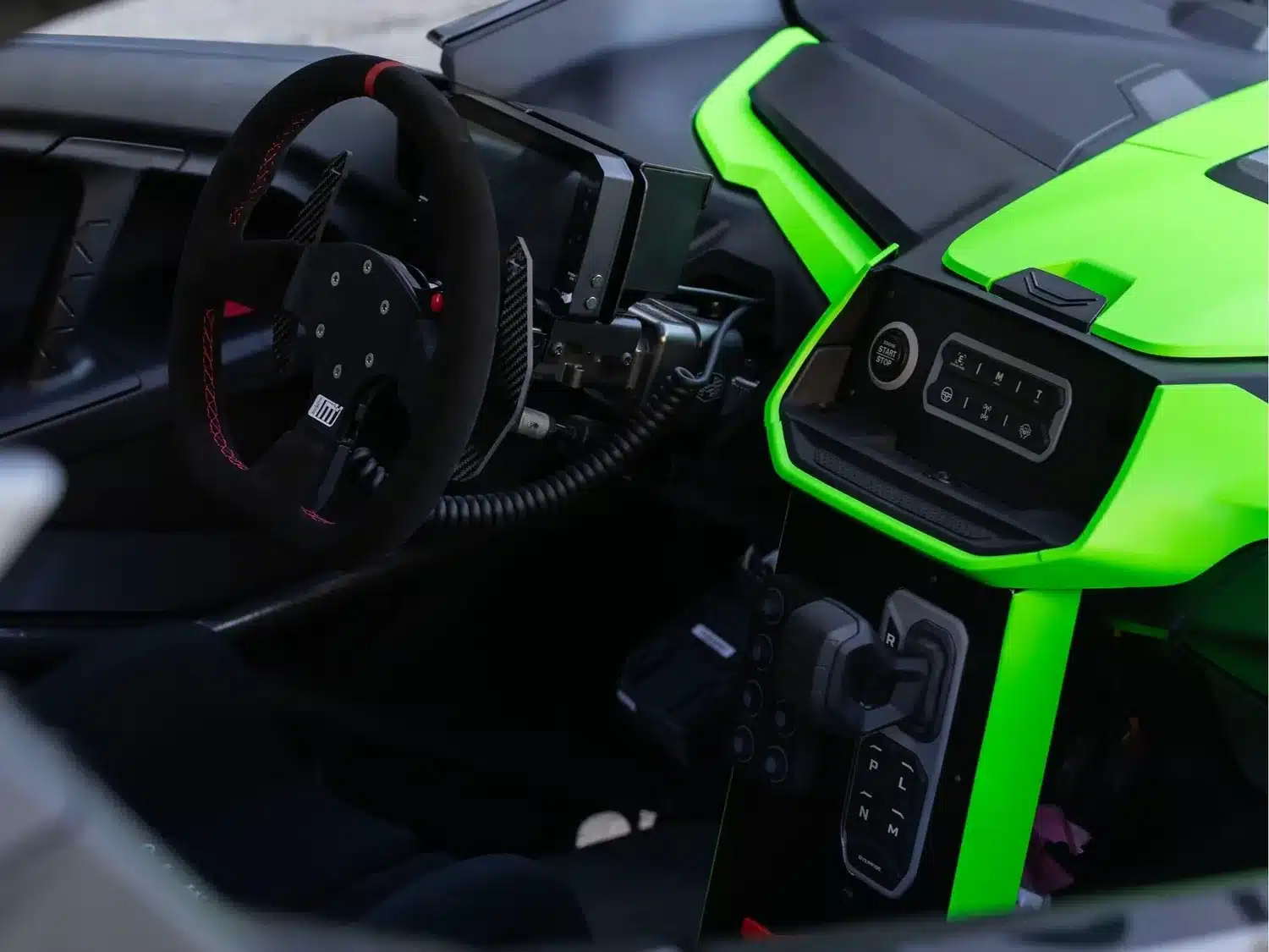 Fahrerorientiertes Cockpit des Stryker Rogue Maverick mit Motorsport-Lenkrad und leuchtend grüner Mittelkonsole.