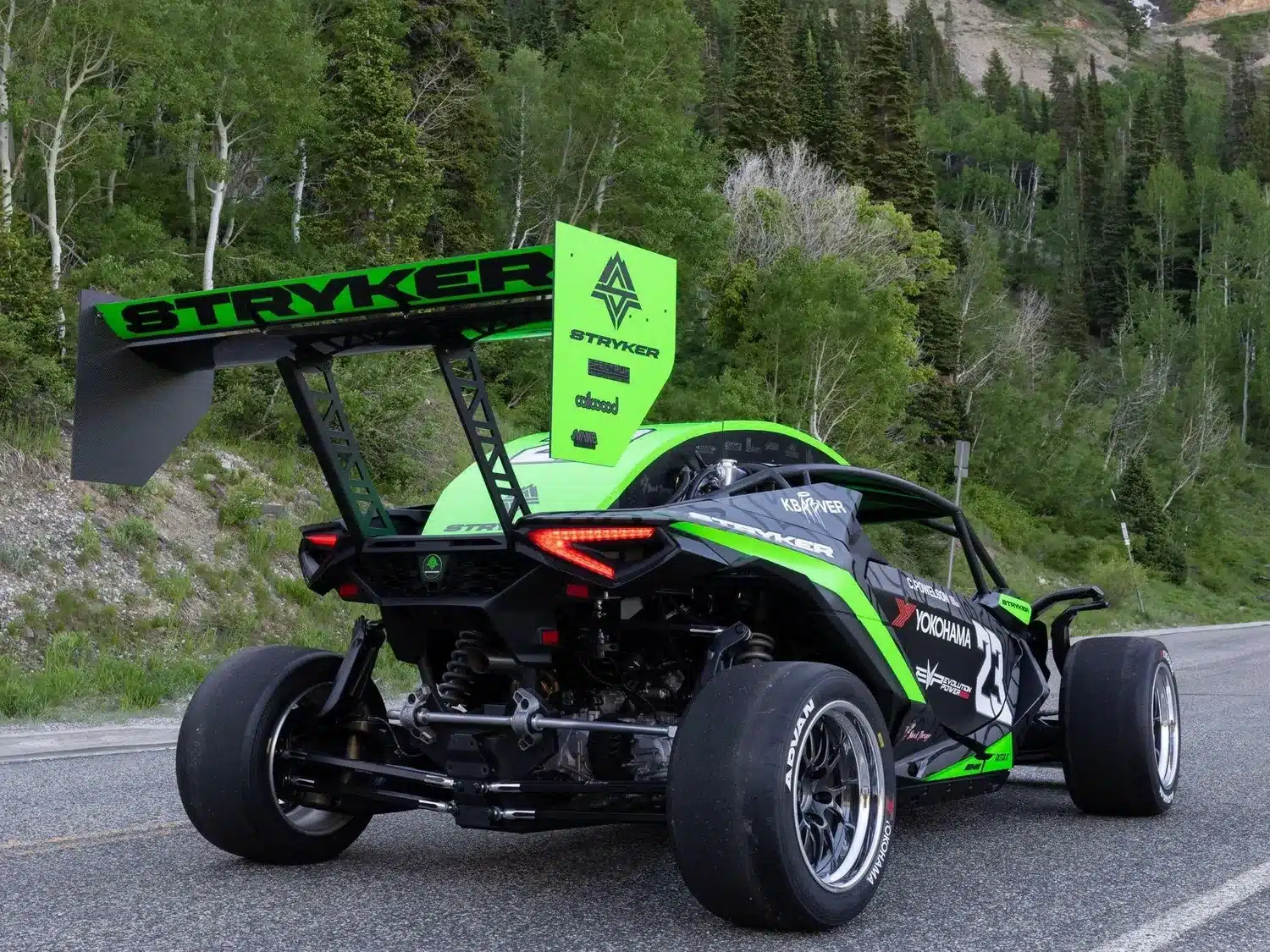 Stryker Rogue Maverick mit auffälligem Heckflügel und Motorsport-Lackierung auf einer Landstraße im Grünen.