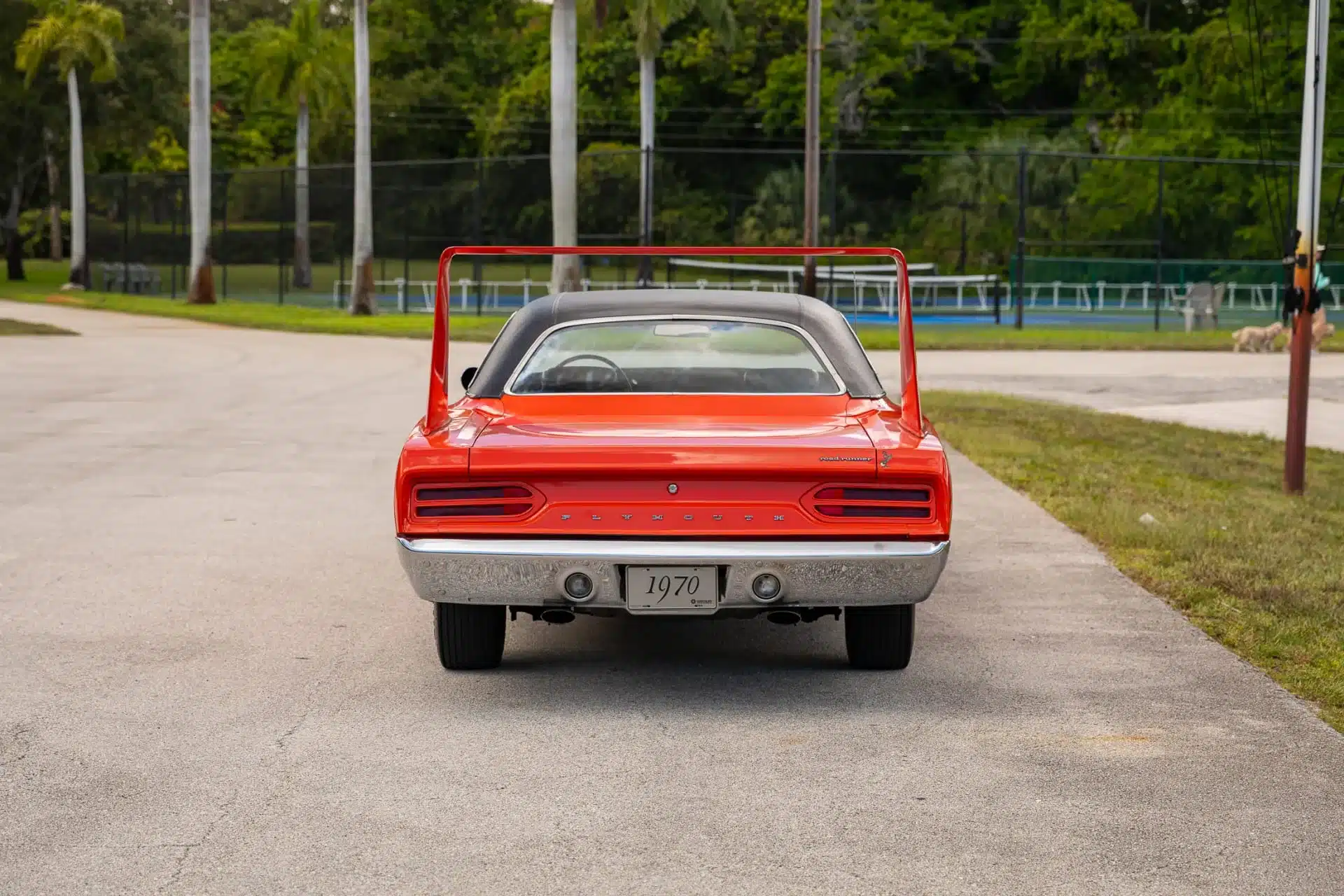 Rückansicht eines orangefarbenen 1970 Plymouth Superbird mit großem Heckflügel auf einer Straße.