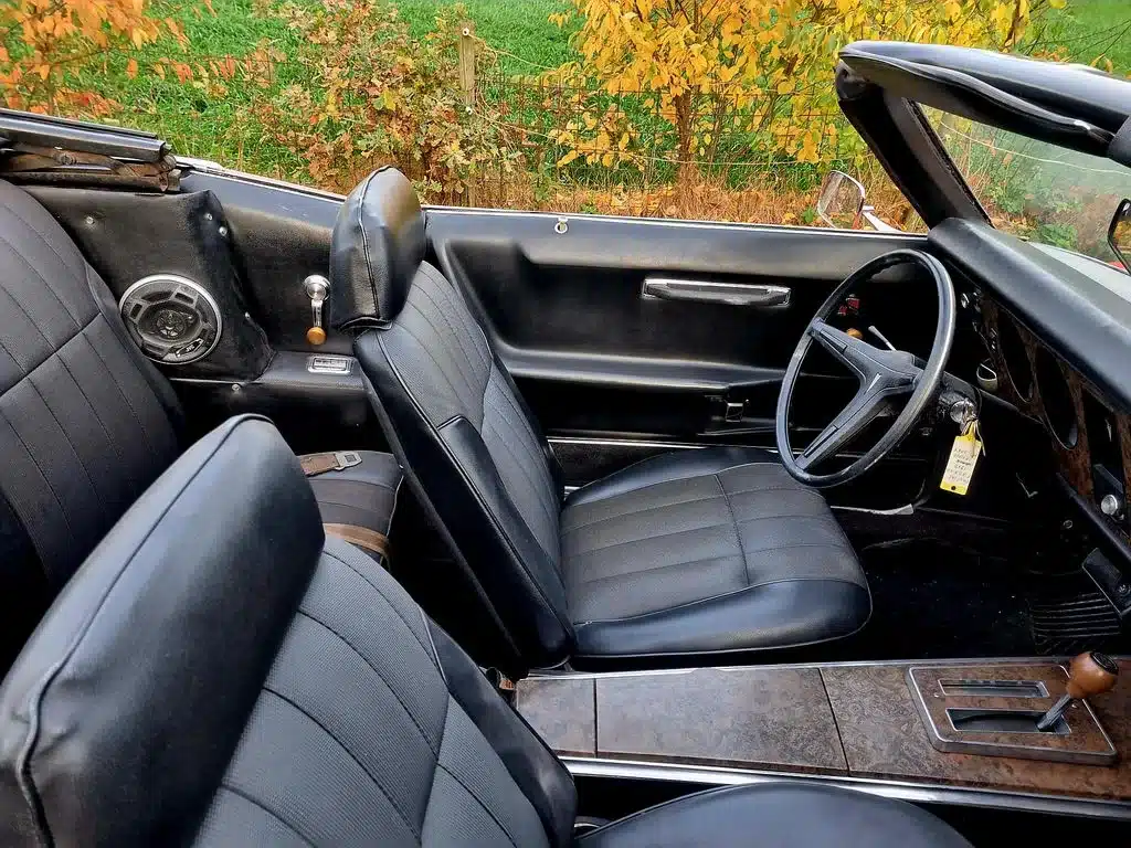 Innenraum eines Pontiac Firebird Cabriolets von 1969 mit schwarzen Sitzen und detailreicher Armatur.